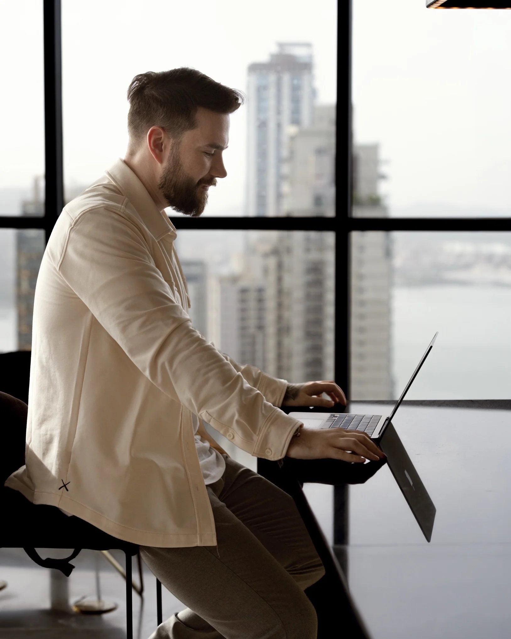 Samuel Peiffer arbeitet am Laptop vor der Skyline, bereitet ein Expertengespräch vor